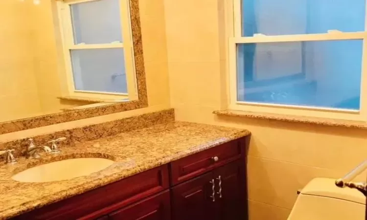 Bathroom with vanity, tile walls, and toilet