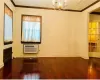 Spare room with a wall mounted AC, crown molding, a notable chandelier, and hardwood / wood-style flooring