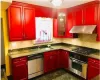 Kitchen featuring appliances with stainless steel finishes, tasteful backsplash, dark stone countertops, and sink