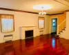 Unfurnished living room with radiator heating unit, an inviting chandelier, dark wood-type flooring, and crown molding