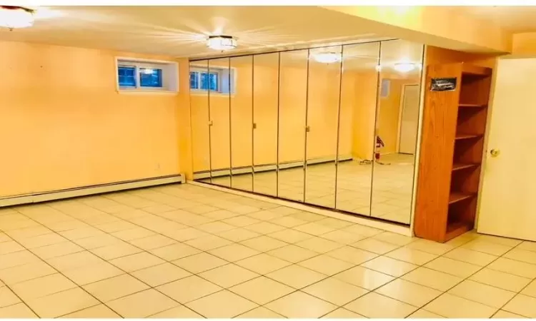 Basement with light tile patterned floors and baseboard heating