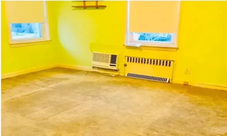 Carpeted empty room featuring radiator heating unit