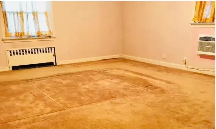 Empty room with radiator heating unit and a wall mounted air conditioner