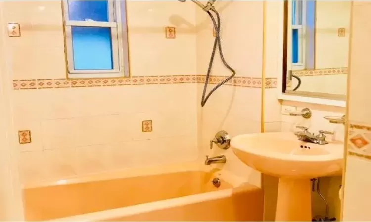 Bathroom featuring tiled shower / bath combo and tile walls