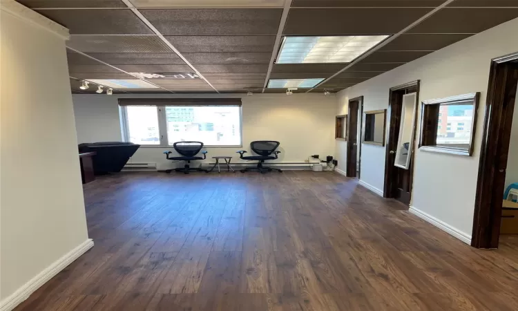 Empty room with baseboard heating and dark hardwood / wood-style floors