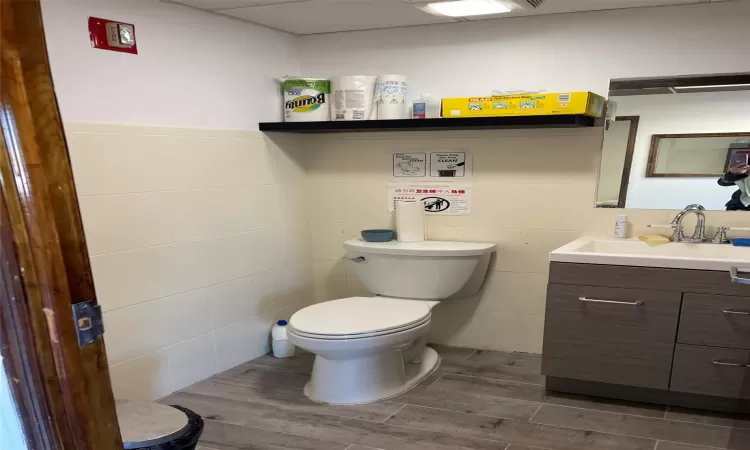 Bathroom featuring hardwood / wood-style flooring, vanity, toilet, and tile walls