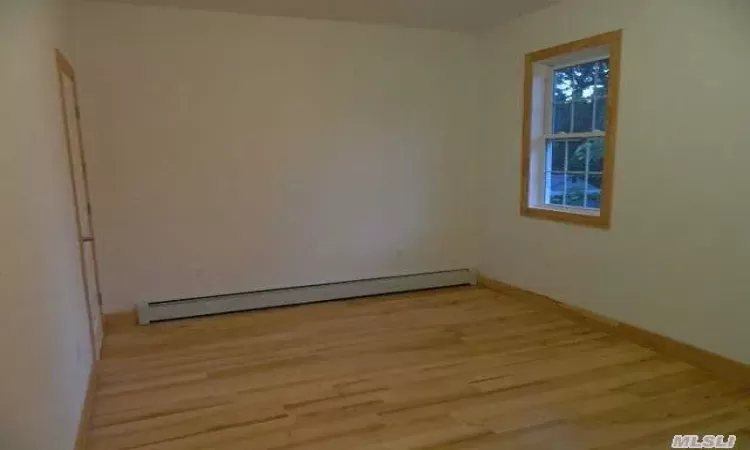 Empty room with light wood-type flooring and a baseboard radiator