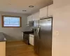 Kitchen with white cabinets, stainless steel appliances, extractor fan, and light wood-type flooring