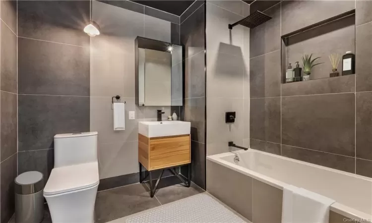 Full bathroom with vanity, toilet, shower / bathing tub combination, tile walls, and tile patterned flooring