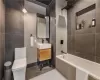 Full bathroom featuring toilet, tile patterned floors, tile walls, washtub / shower combination, and vanity