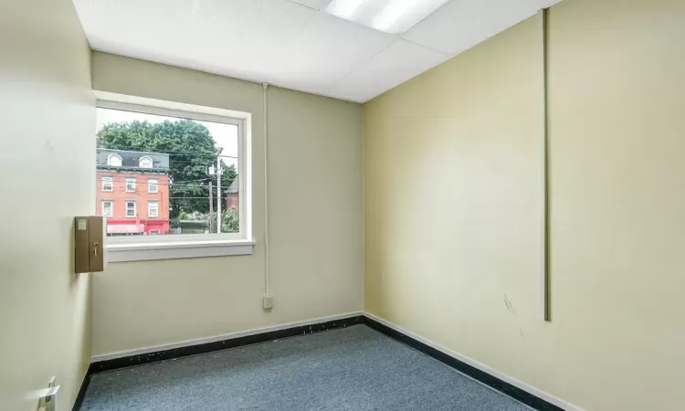 Empty room with a drop ceiling and carpet floors