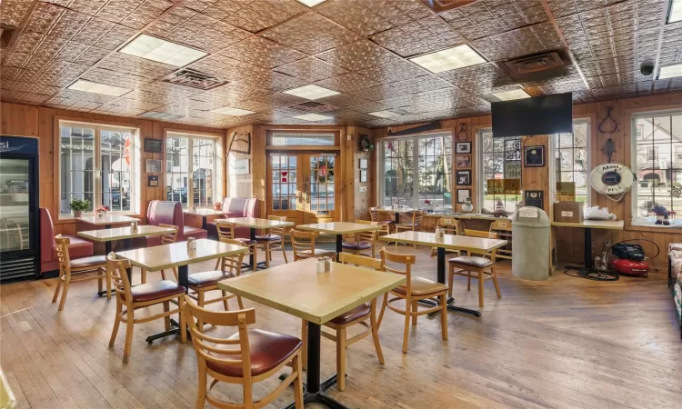 Dining area with hardwood / wood-style floors, wood walls, and french doors