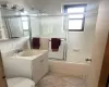 Full bathroom with backsplash, bath / shower combo with glass door, vanity, tile patterned flooring, and toilet