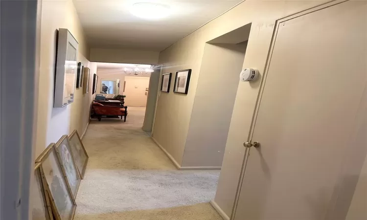 Hall with a chandelier and light colored carpet