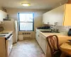 Kitchen featuring decorative backsplash, radiator heating unit, white appliances, and white cabinetry