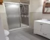 Bathroom with vanity, tile patterned floors, toilet, tile walls, and a shower with shower door