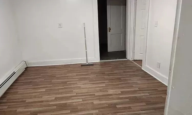 Spare room with dark hardwood / wood-style flooring and a baseboard radiator