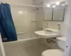 Full bathroom with tile patterned floors, sink, toilet, tile walls, and shower / tub combo