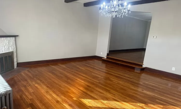 Unfurnished room featuring radiator heating unit and dark wood-type flooring