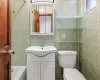 Full bathroom with shower / tub combination, vanity, toilet, and tile walls