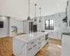 Kitchen featuring quartz countertops, decorative light fixtures, white cabinets, and a kitchen island