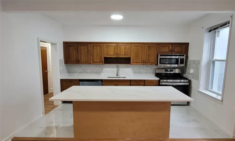 Kitchen featuring backsplash, sink, a kitchen island, and appliances with stainless steel finishes