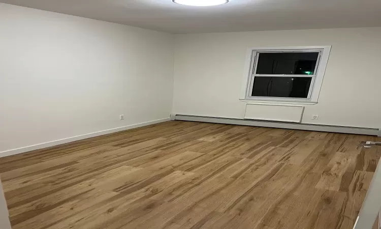 Spare room with a baseboard radiator and light hardwood / wood-style flooring