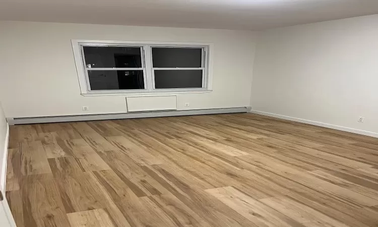 Spare room featuring baseboard heating and light hardwood / wood-style flooring