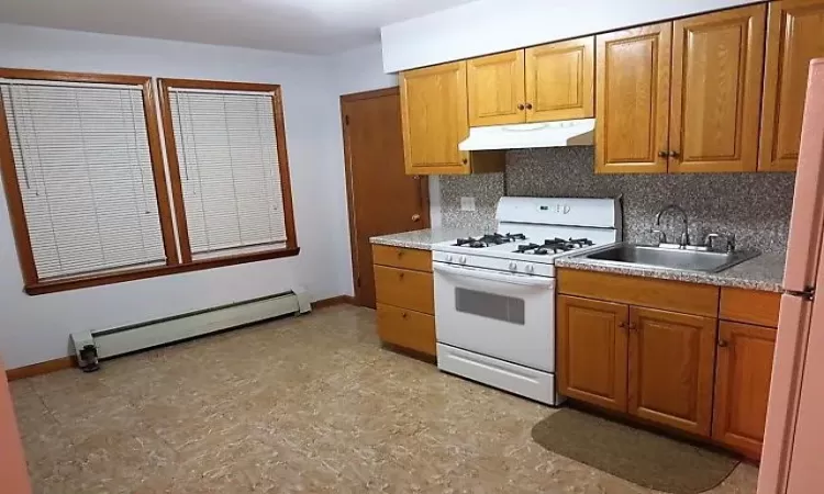 Kitchen with backsplash, sink, white appliances, and a baseboard heating unit