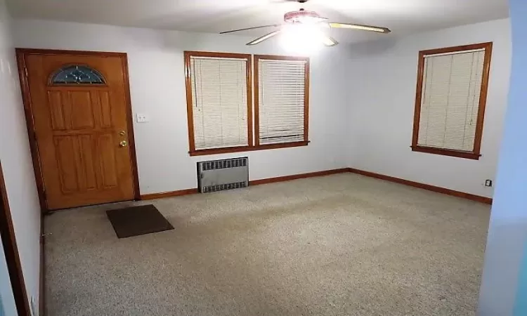 Carpeted foyer entrance with radiator and ceiling fan