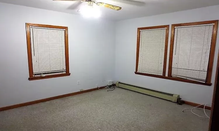 Unfurnished room featuring a baseboard radiator and ceiling fan