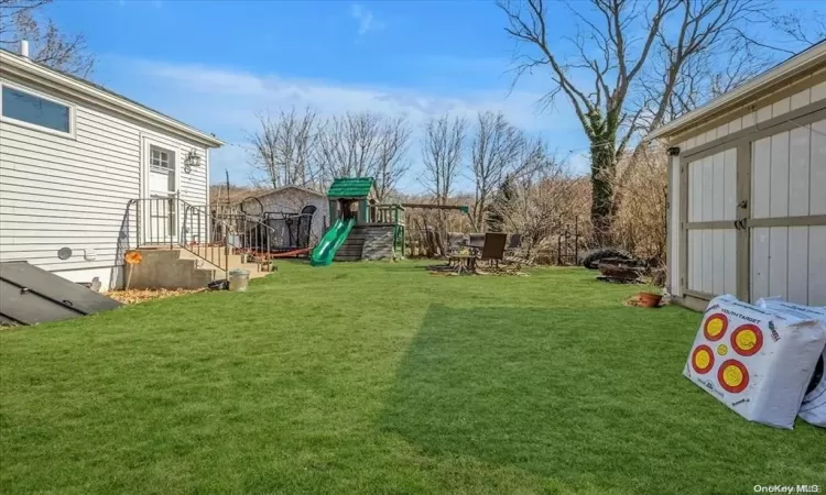 View of yard featuring a playground and a shed