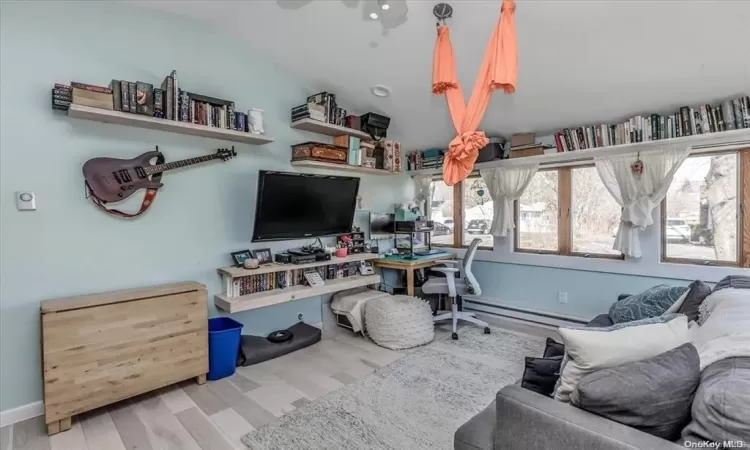 Office area with baseboard heating, light hardwood / wood-style floors, and lofted ceiling