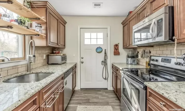 Kitchen featuring light stone counters, stainless steel appliances, and hardwood / wood-style flooring