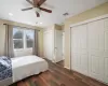 Bedroom with ceiling fan, dark hardwood / wood-style floors, and two closets