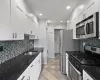 Kitchen with tasteful backsplash, stainless steel appliances, sink, dark stone countertops, and white cabinets