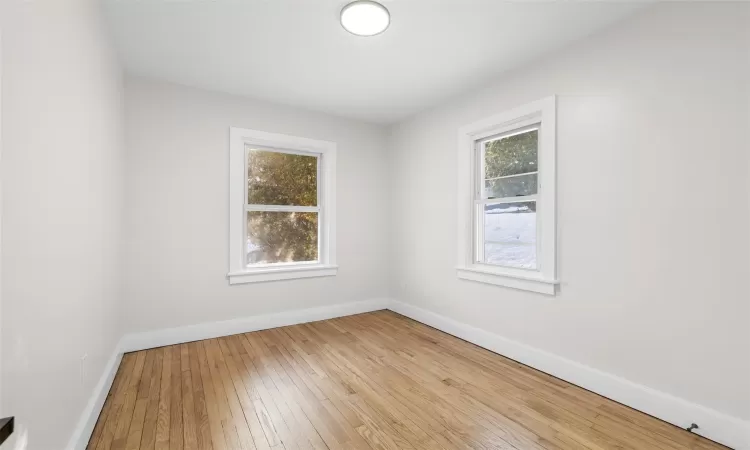 Bedroom 2 with hardwood floors. Unfurnished.