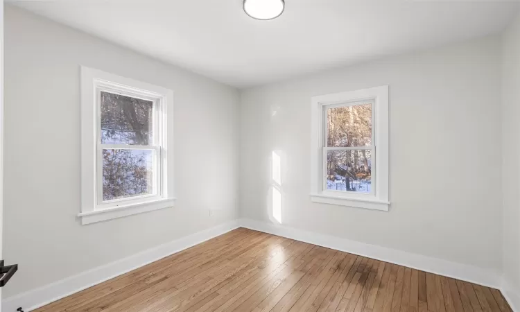 Bedroom 1 featuring light hardwood floors.  Unfurnished.