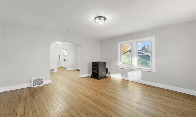 Unfurnished living room featuring light hardwood floors and pellet stove.