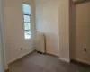 Empty room with carpet flooring, a wall mounted air conditioner, and radiator