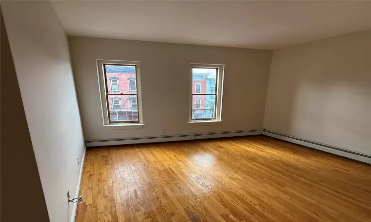 Spare room with baseboard heating and light wood-type flooring