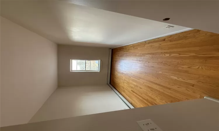 Unfurnished room featuring light wood-type flooring and a baseboard heating unit