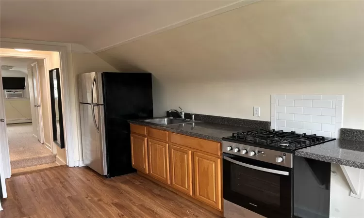 Kitchen with cooling unit, sink, vaulted ceiling, appliances with stainless steel finishes, and wood-type flooring