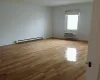 Unfurnished room with a wall mounted air conditioner, light wood-type flooring, and a baseboard radiator