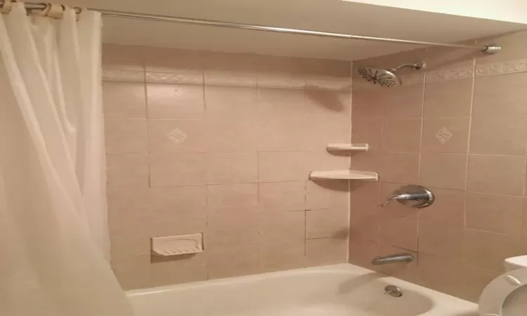 Bathroom with toilet and shower / bathtub combination with curtain