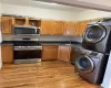 Kitchen with stacked washer / dryer, sink, light hardwood / wood-style floors, and appliances with stainless steel finishes