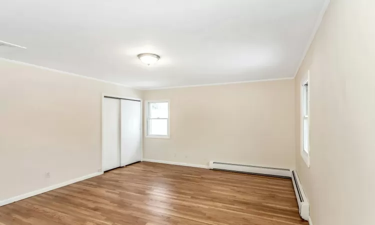 Spare room with hardwood / wood-style flooring, crown molding, a chandelier, and a baseboard heating unit