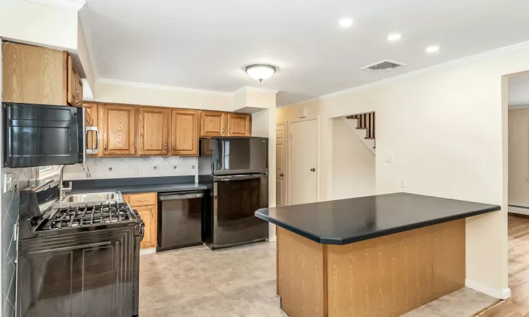 Kitchen with an inviting chandelier, black appliances, hanging light fixtures, baseboard heating, and tasteful backsplash