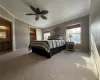 Carpeted bedroom featuring a textured ceiling, multiple windows, ceiling fan, and vaulted ceiling