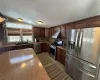 Kitchen with dark brown cabinets, lofted ceiling, sink, and appliances with stainless steel finishes